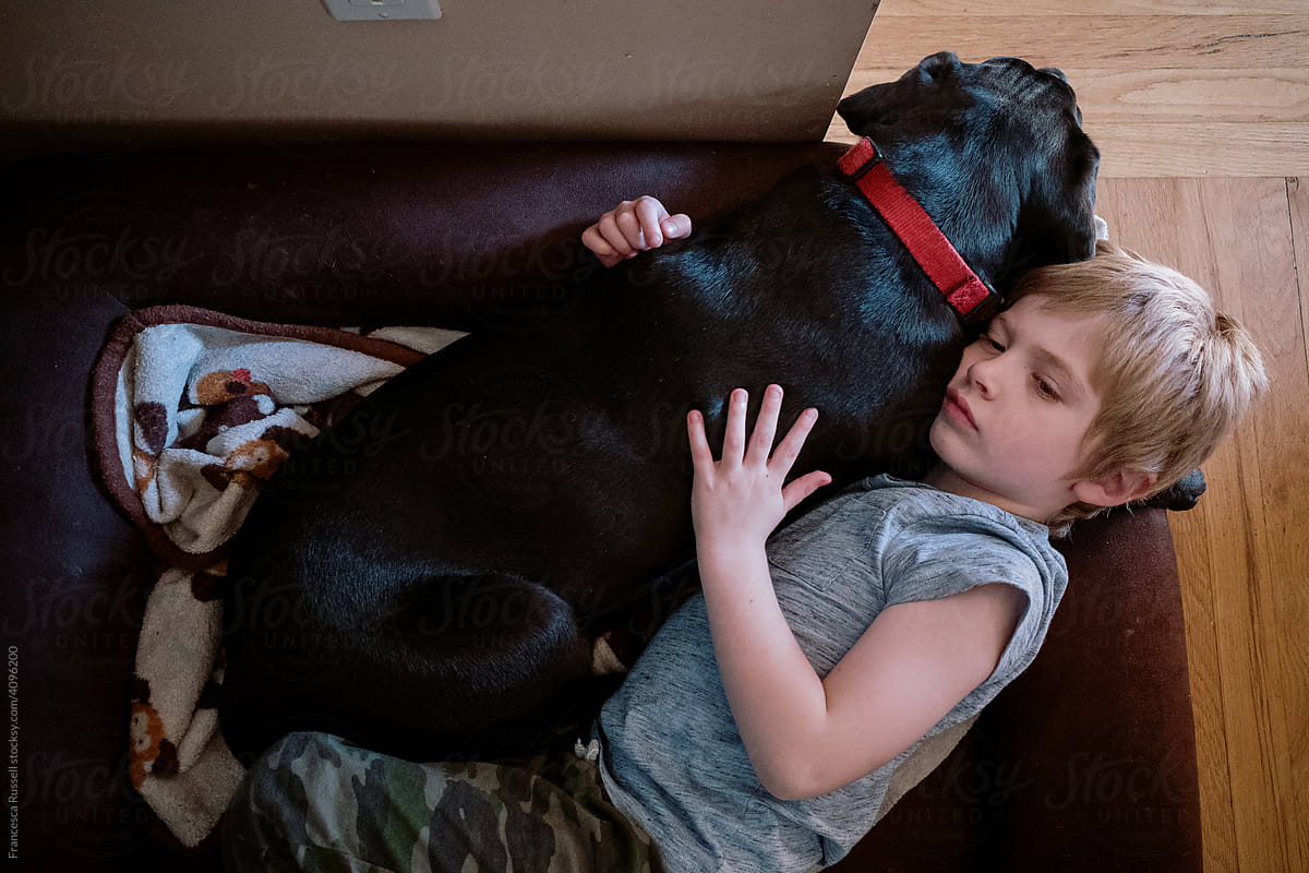 A little boy lies down with his dog.
