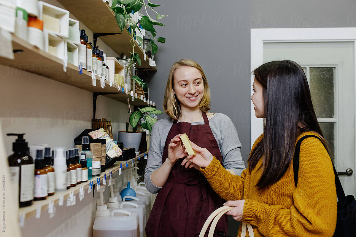 Seller offering buyer piece of soap to view in organic shop