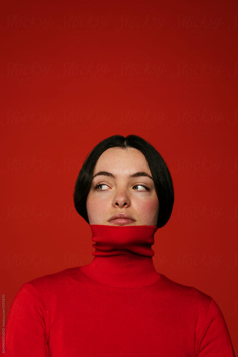 Thoughtful woman standing on red wall