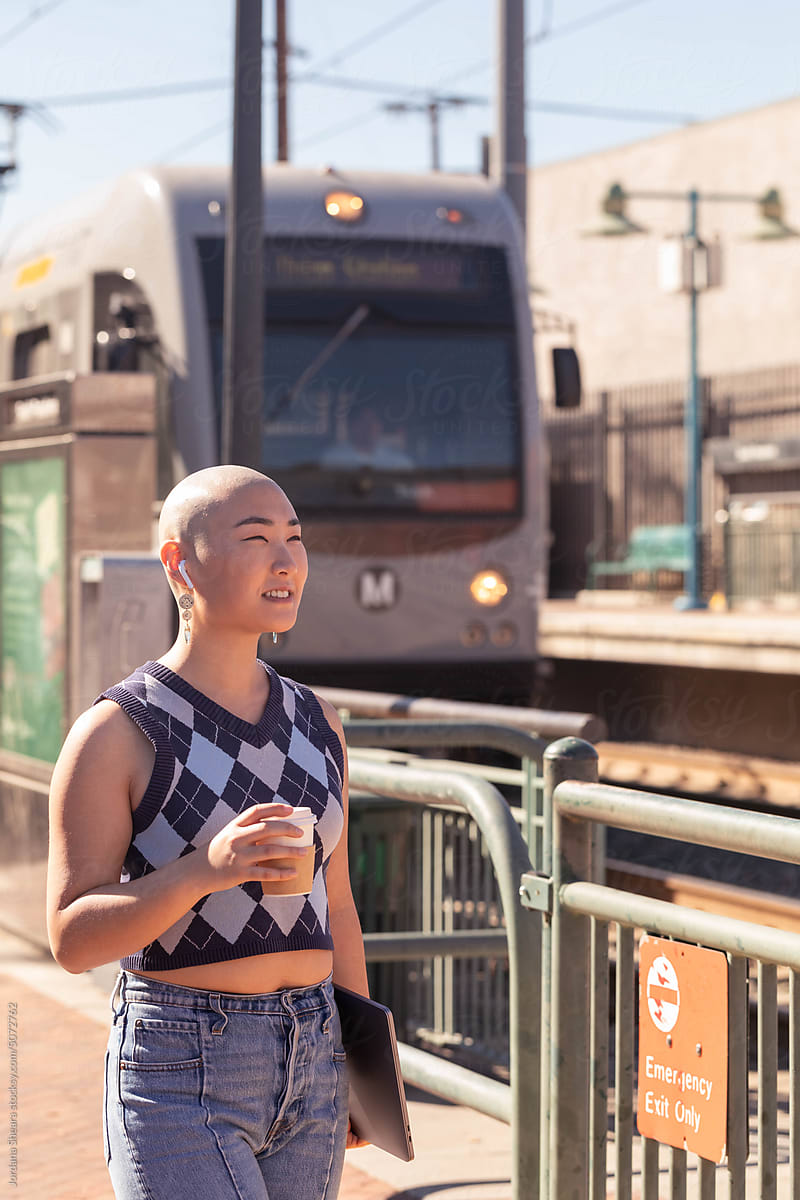 Stylish Gen Z woman walking with metro train in the background