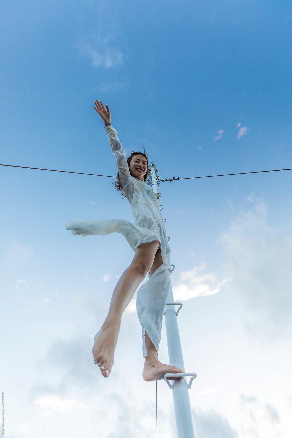A asian woman with white dress climbing mast stretch her arm and leg