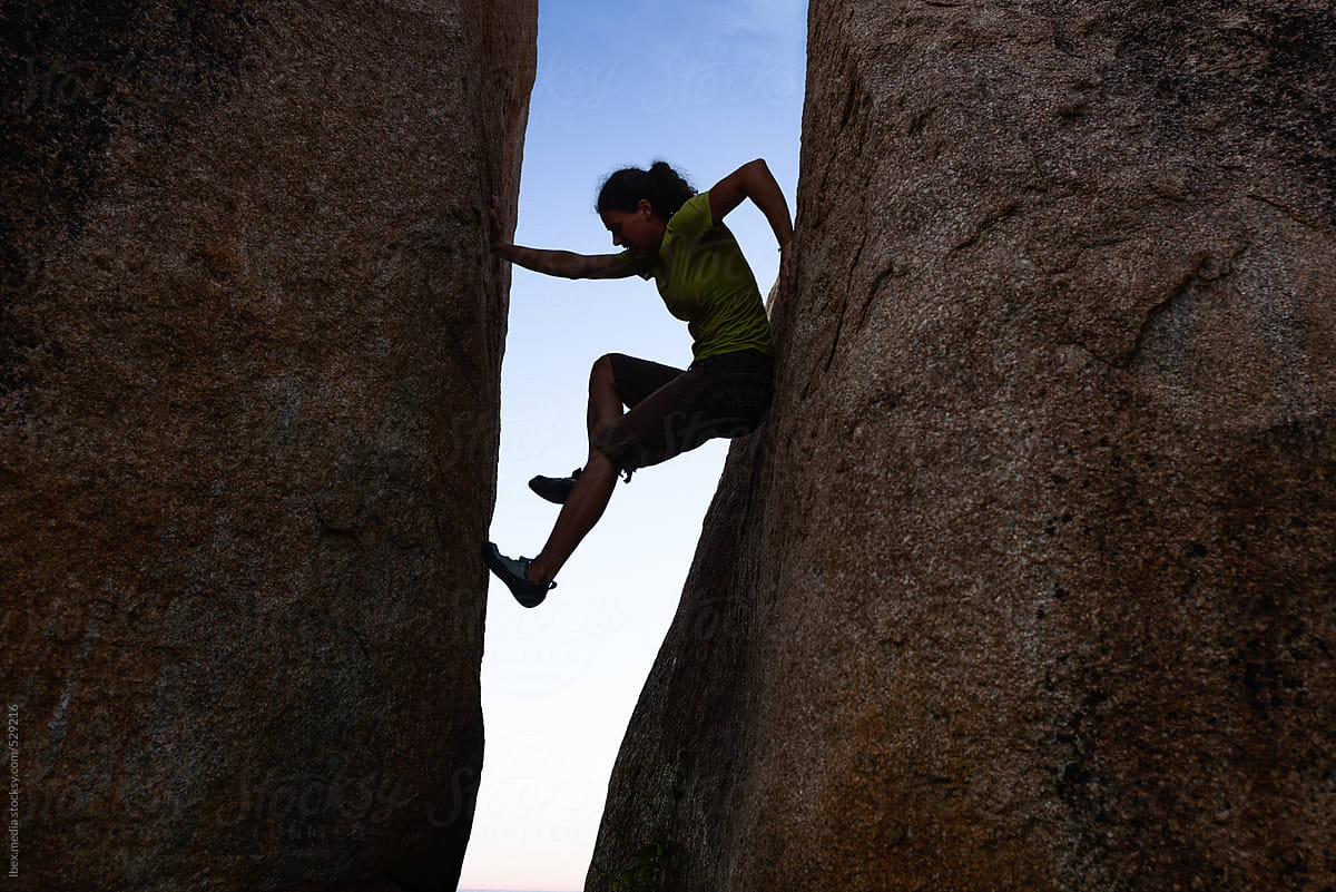 Woman silhouette climbing between two rock walls