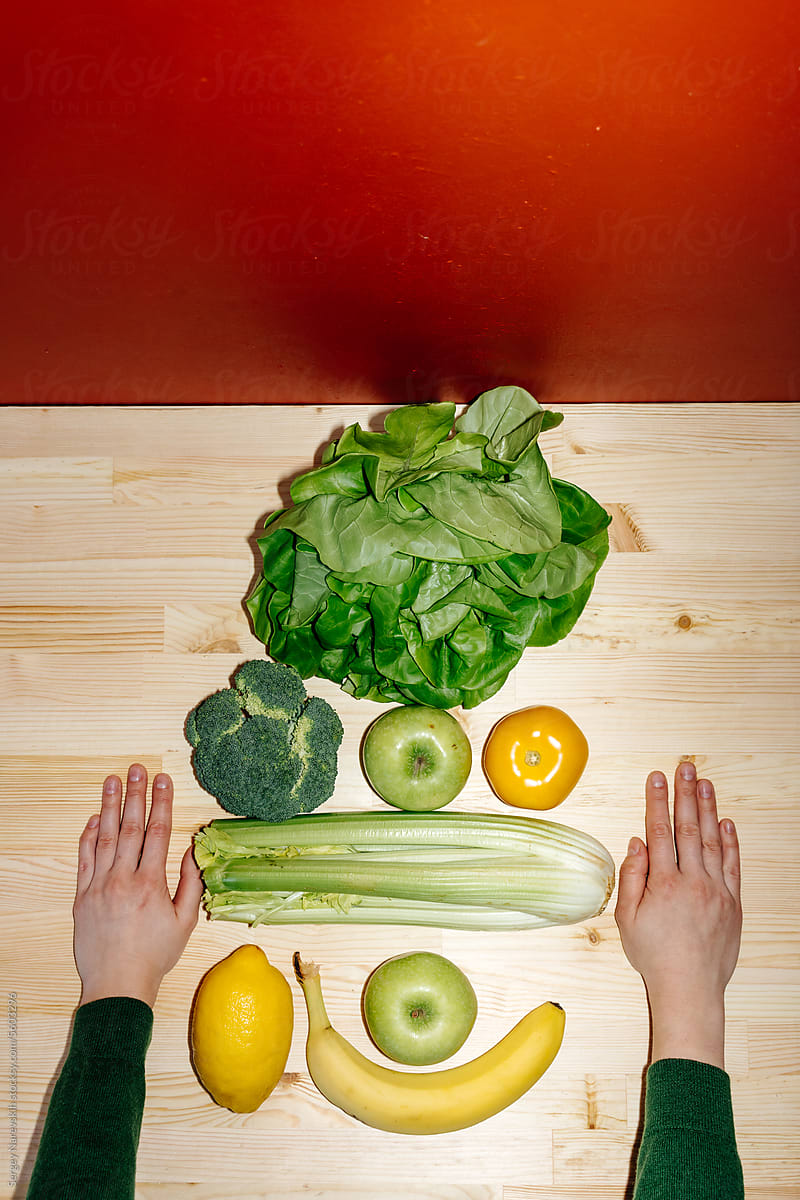 Various green and yellow groceries with hands on table