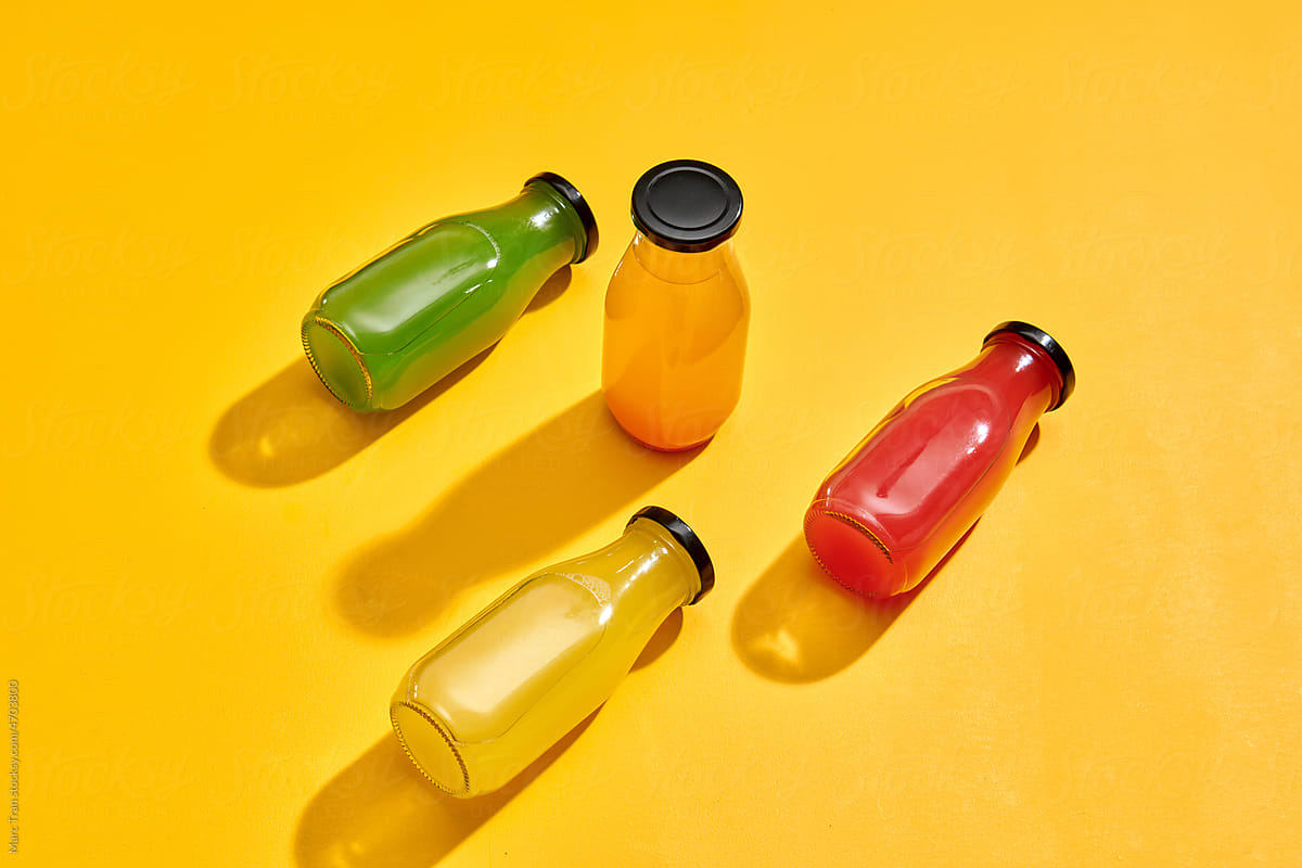Fresh organic juices in bottles for fitness diet on yellow
