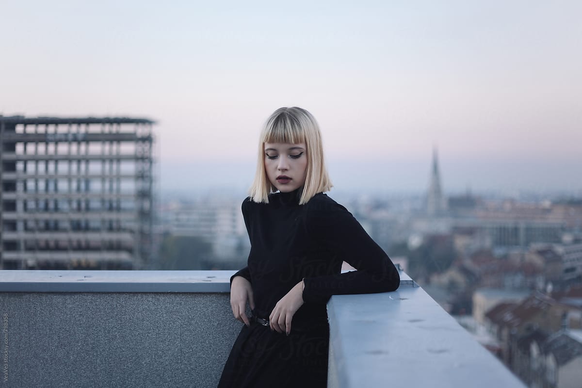 Portrait of a beautiful blonde woman on the roof of the building during sunset