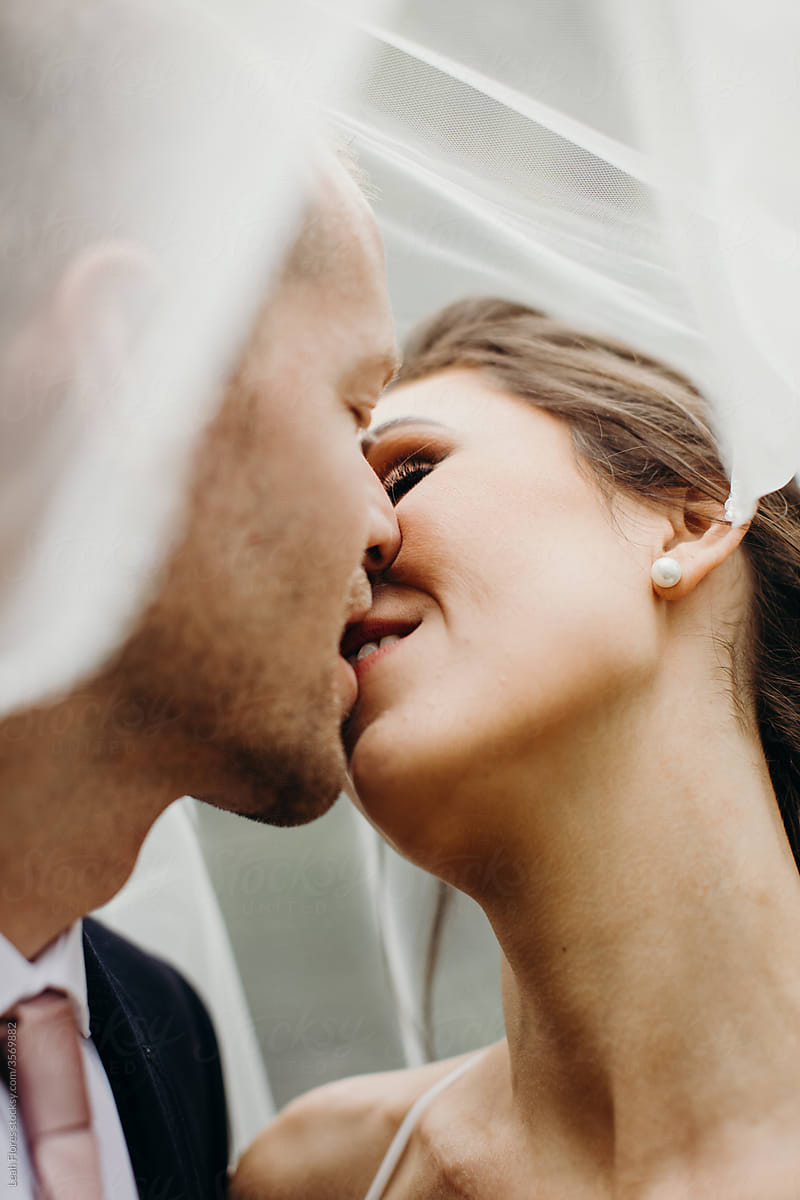Bride and Groom in Romantic Kiss under Veil