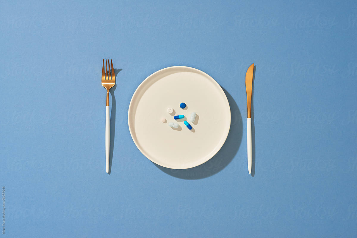 Pills served with spoon and fork in plate on the table