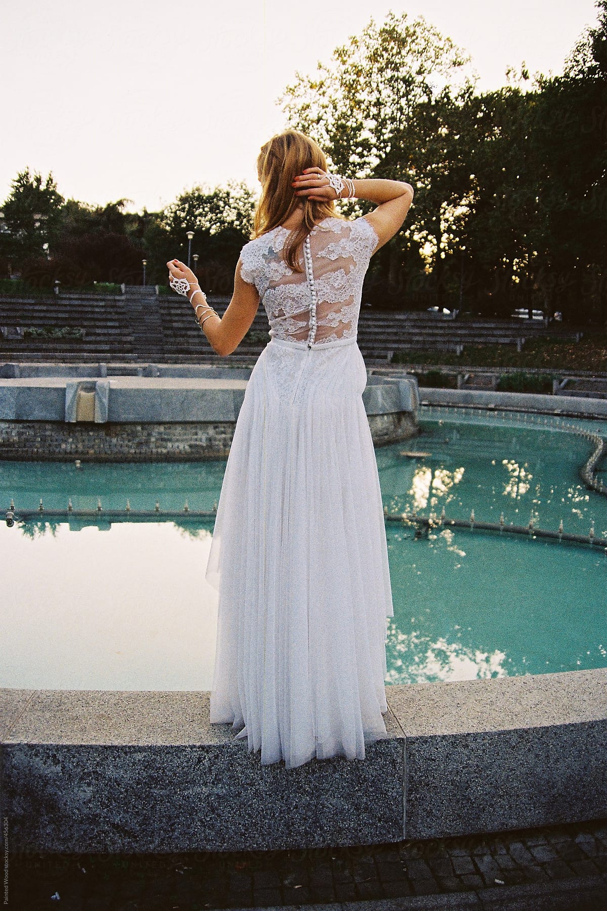 Bride in a romantic wedding dress in front of a fountain