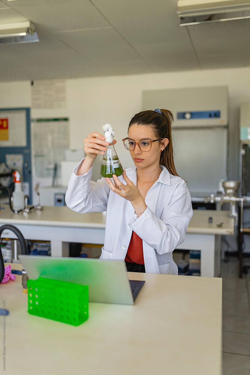 Focused biologist in lab coat examining chemical substance
