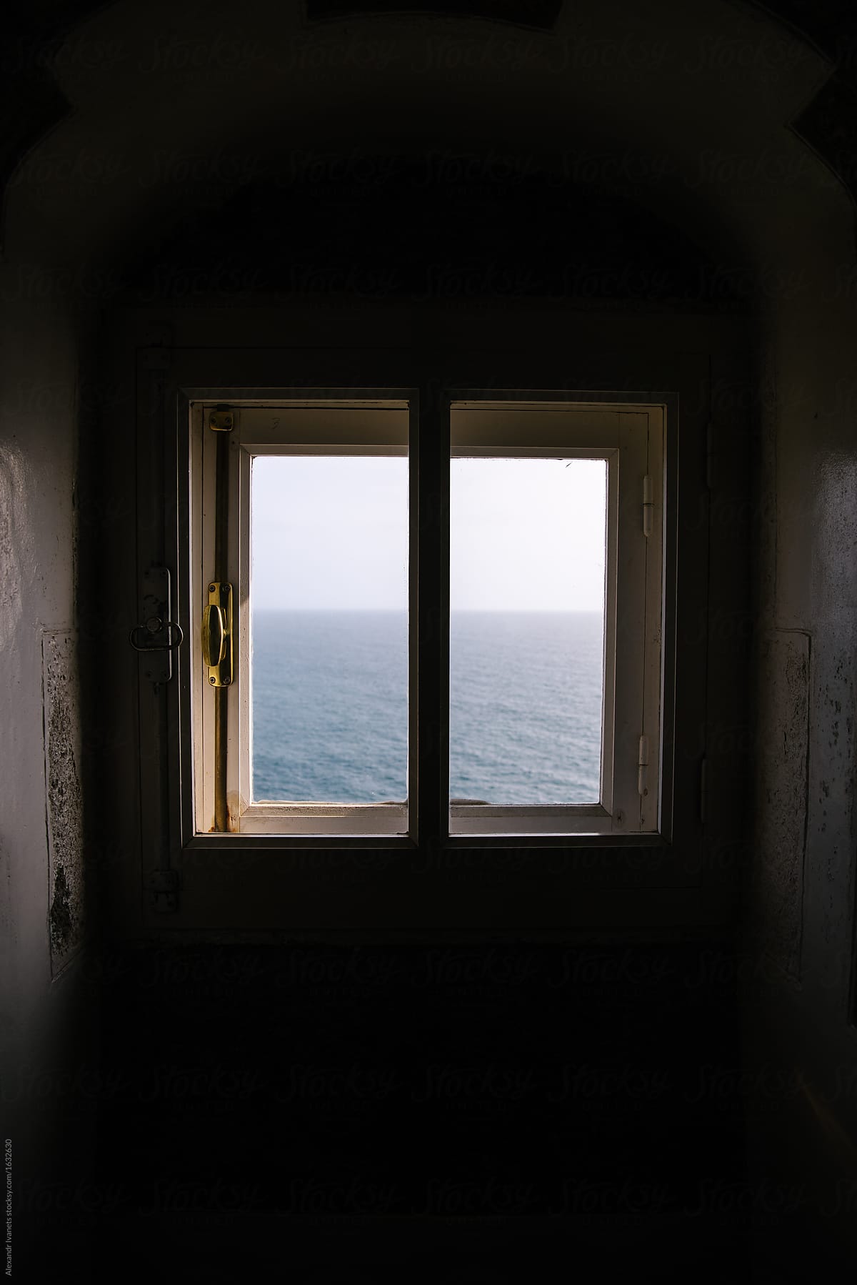 Window in shabby wall with sea behind