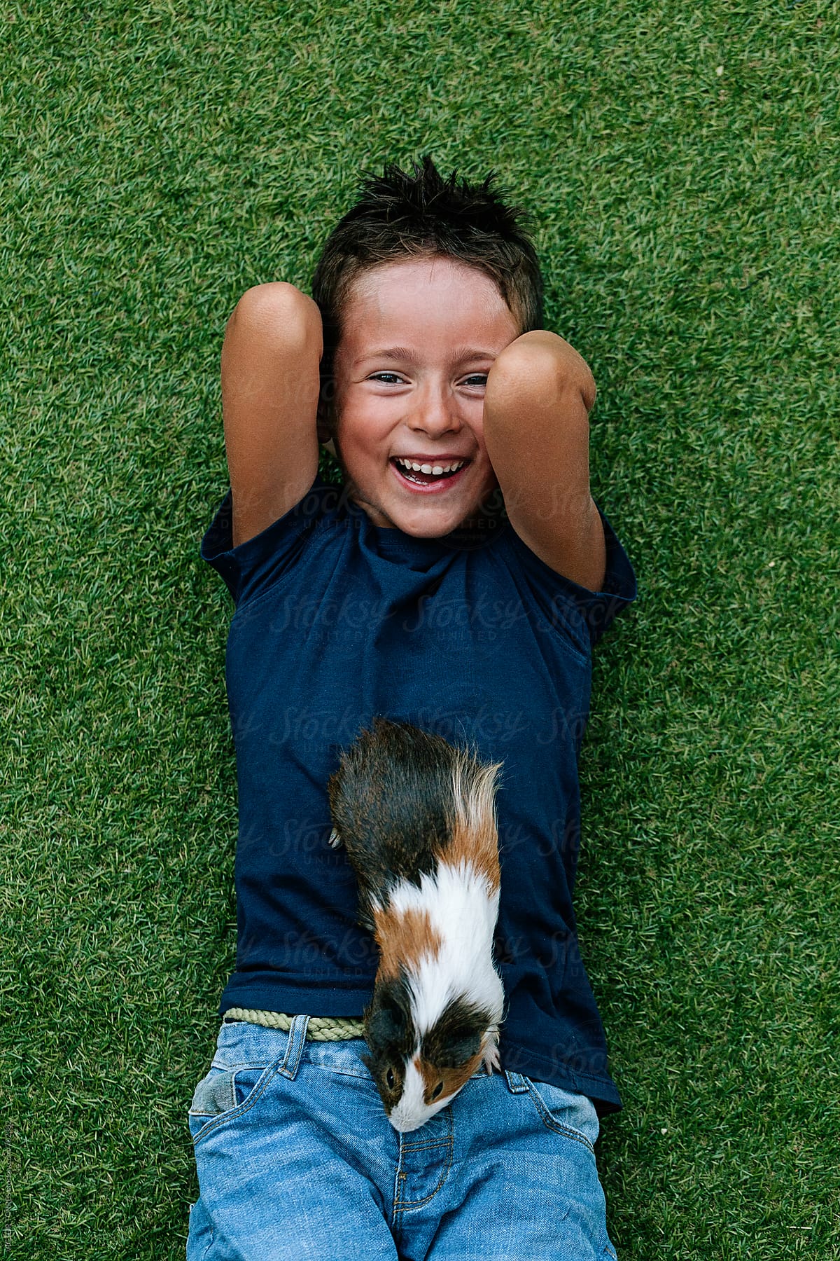 Cute Kid Playing with a Guinea Pig Lying on Grass