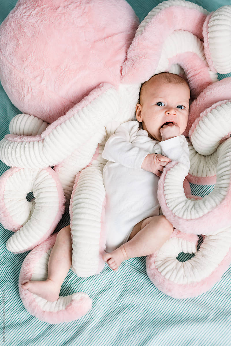 Baby laying on a bed in a plush octopus