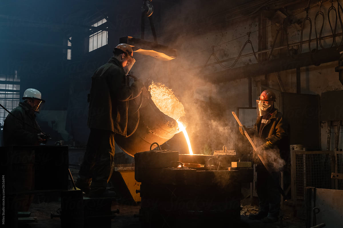 Men working with metal in dark foundry