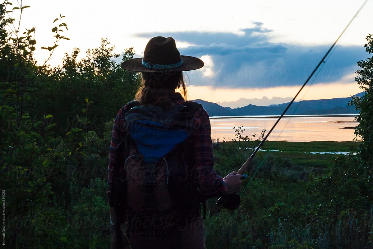 Woman Walks Home After Fly-fishing On A Summer Evening by Stocksy
