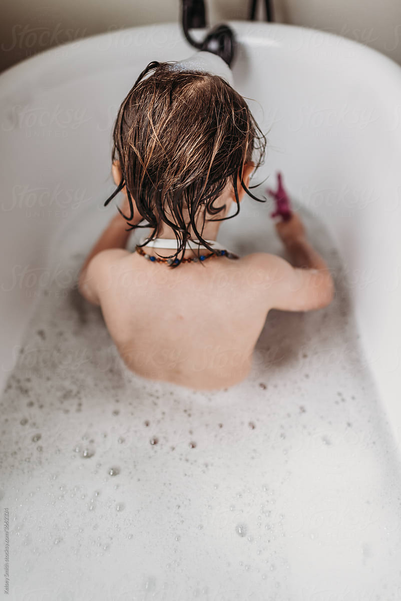 Long haired boy playing in bathtub