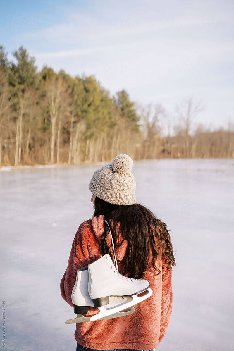 young woman by lake holding skates