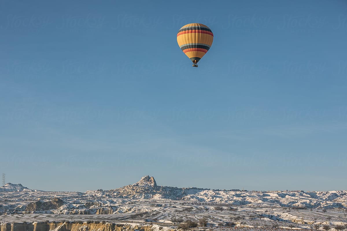 colorful hot air balloon above snowcovered city of uchisar, cappadocia, turkey