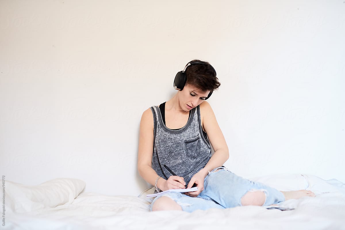 Woman sitting on bed in headphones