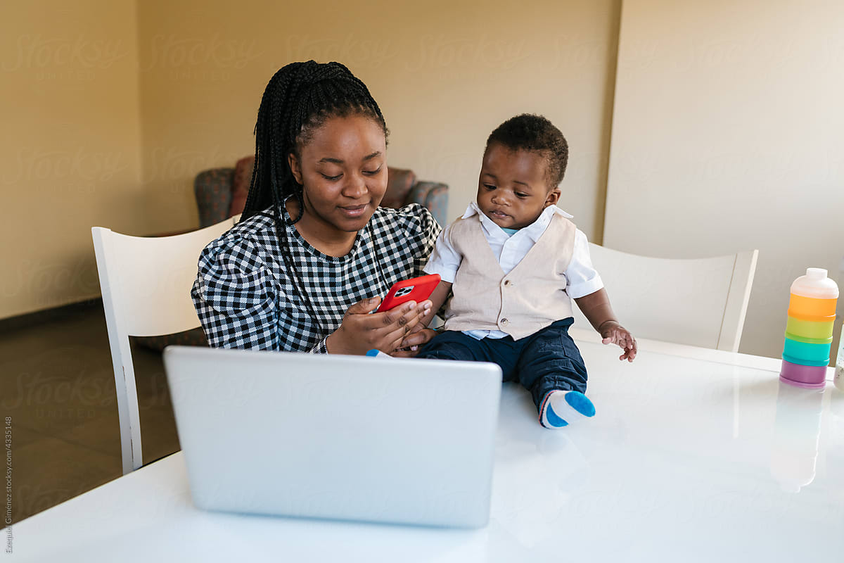 Black mom with baby using cellphone during work