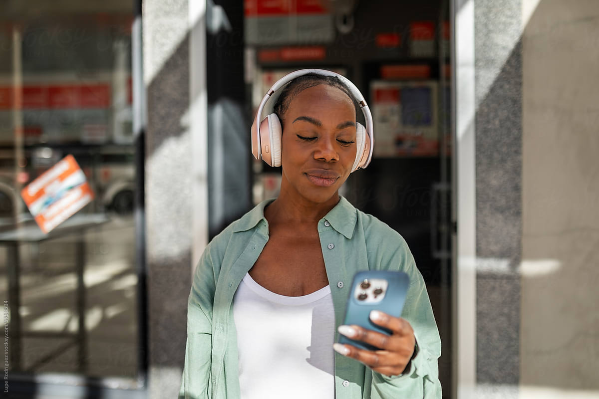 portrait of black woman with headphones at the door of a laundromat