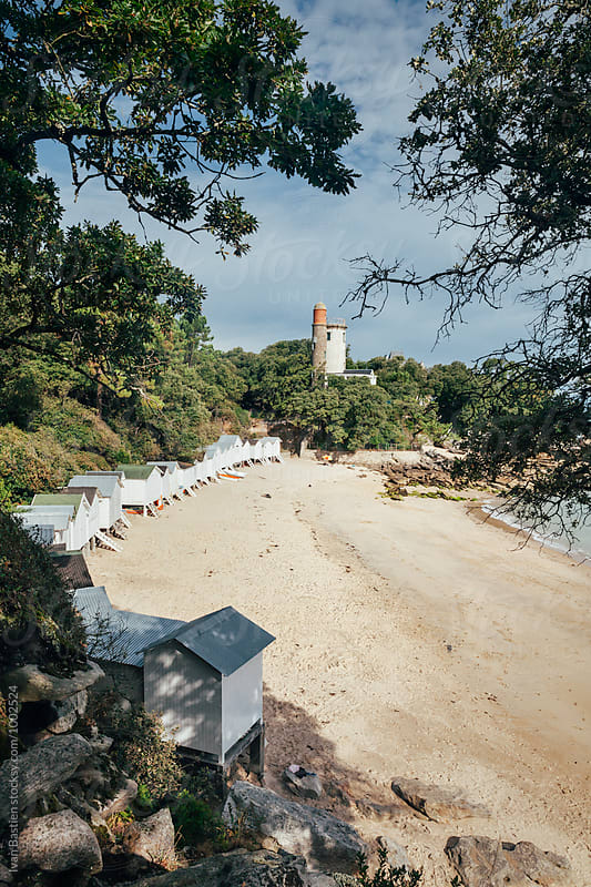 Old huts and lighthouse on Noirmoutier Island beach in France