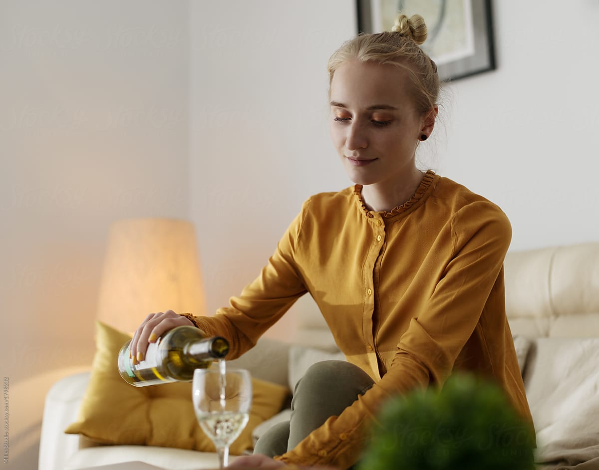 Woman pouring wine and relaxing at home