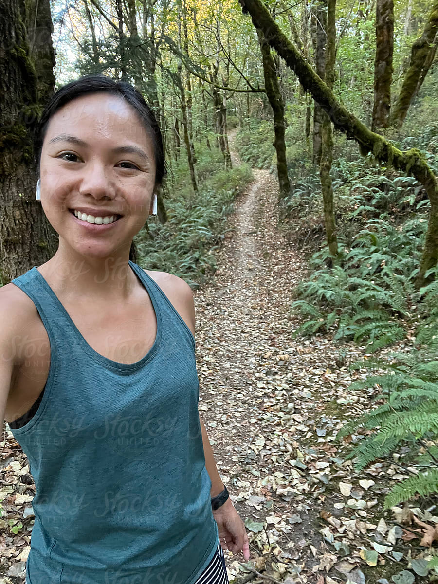 Real ugc selfie of young woman on a trail run in the forest.