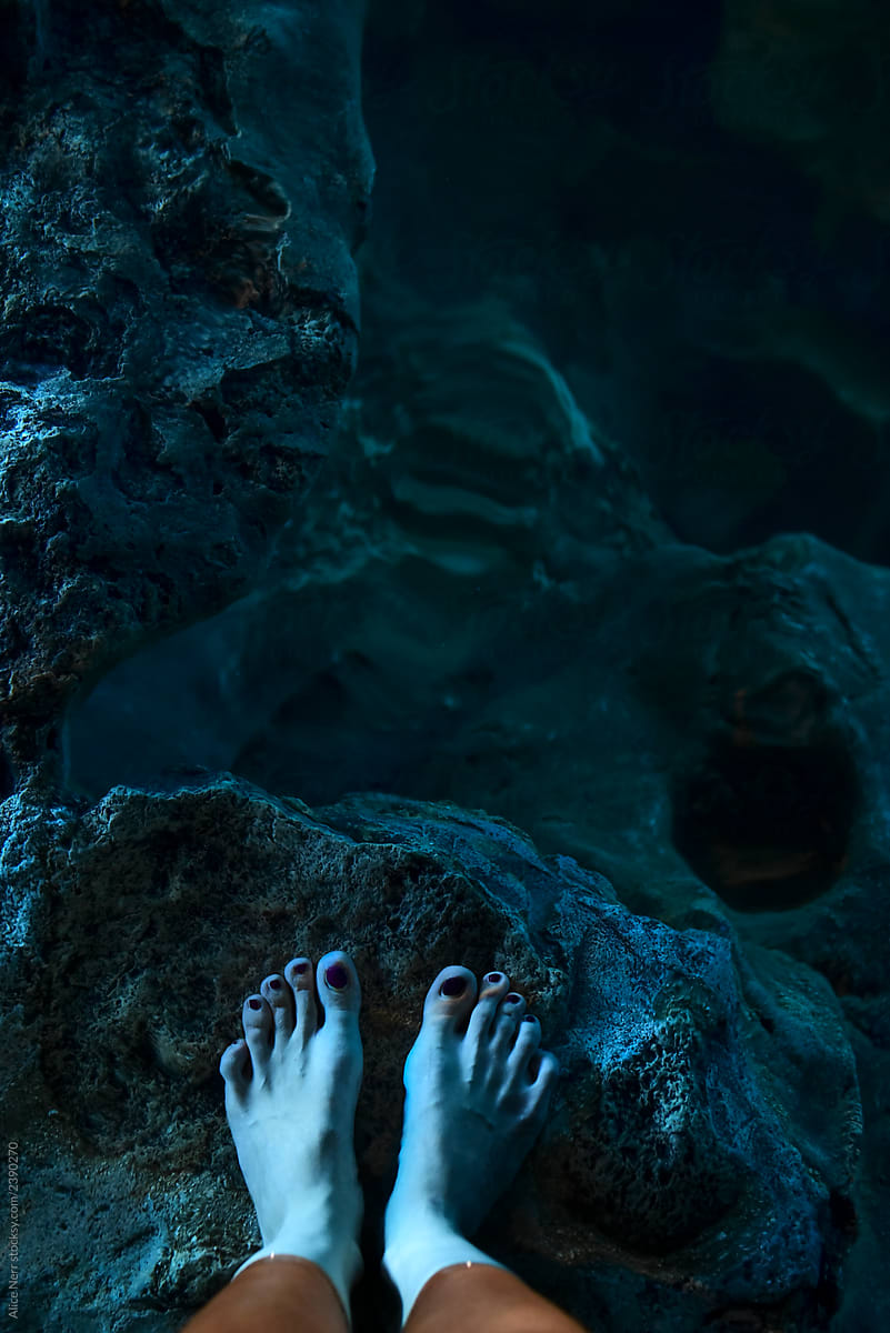 Underwater feet in glowing water of a cave