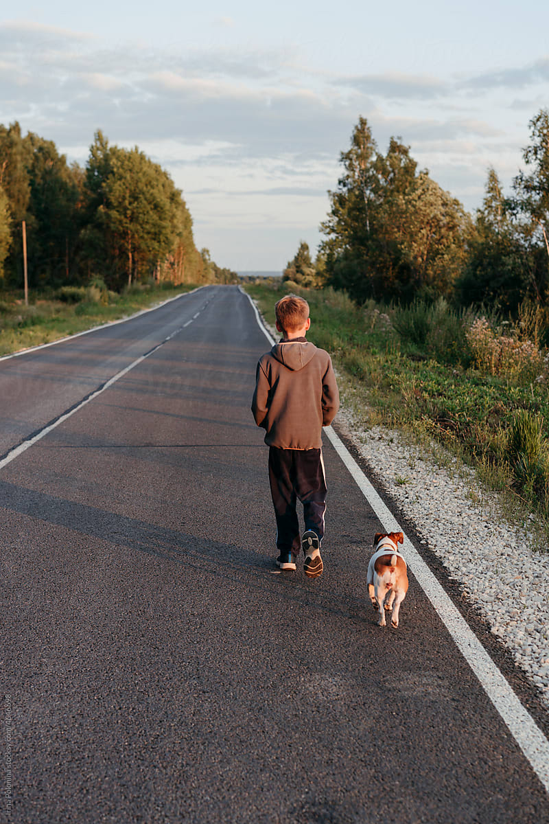 Faceless young boy walks with pet dog.