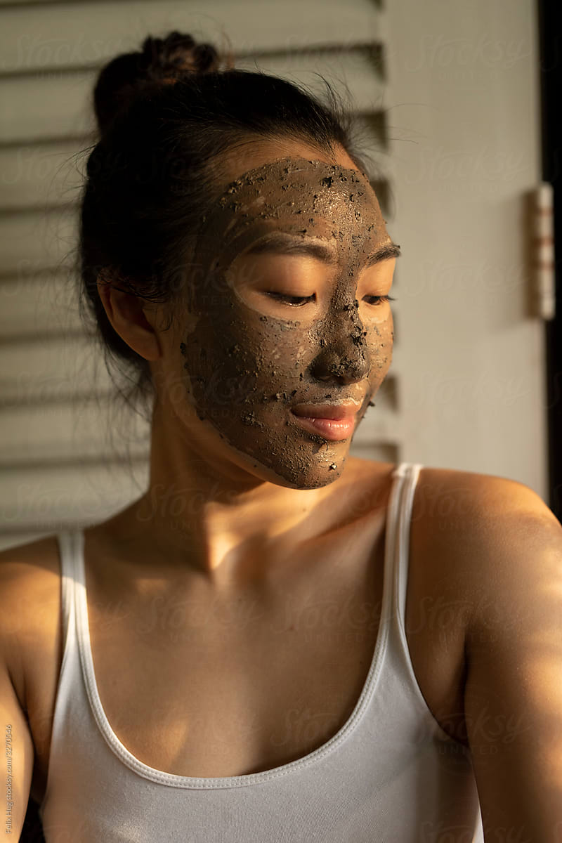 Young asian woman with a mud face-mask her eyes closed.