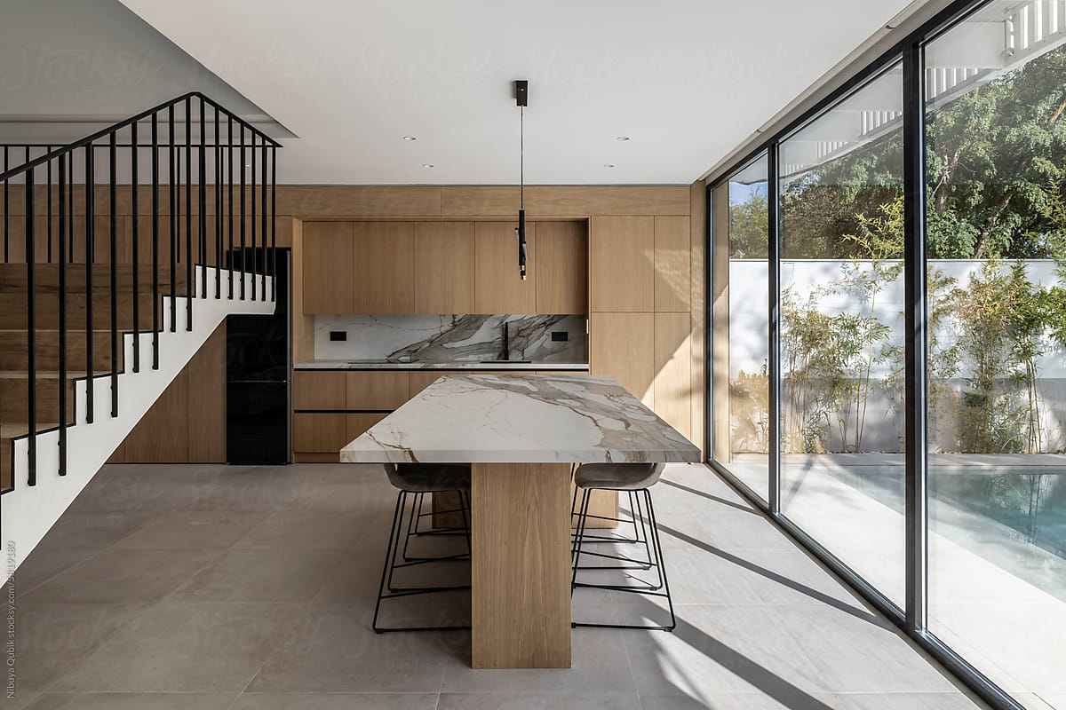 A minimalist kitchen of wood and marble with views to the garden