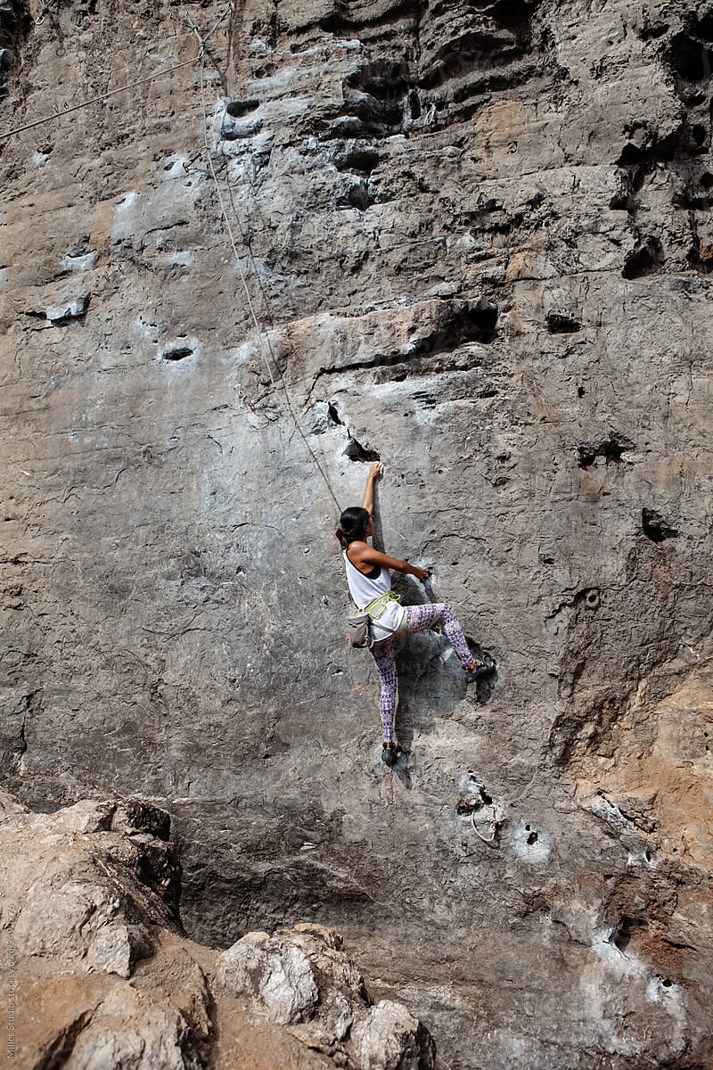 Woman climbing on rocky cliff