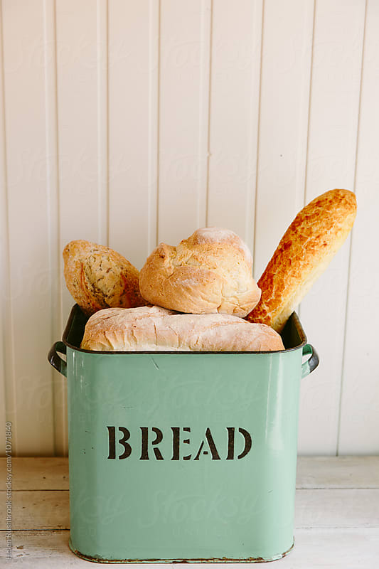 Various types of bread in a vintage bread bin.