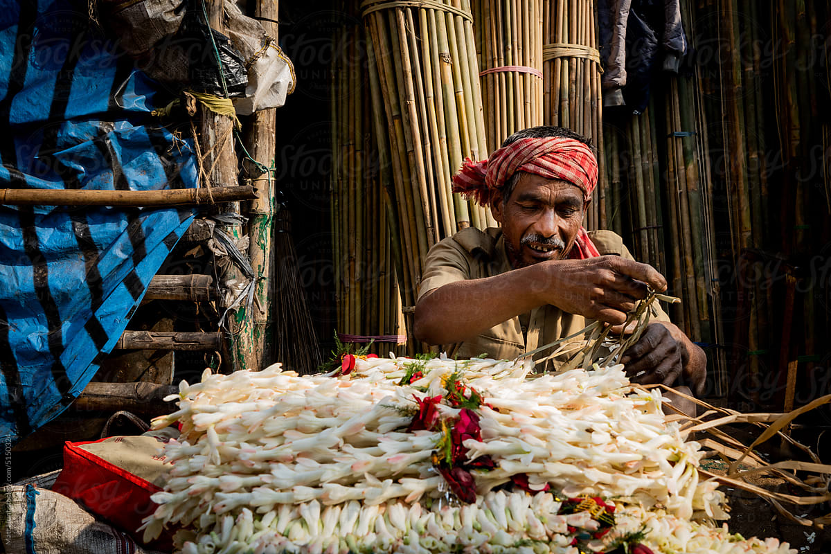 A vendor ties flowers into bundles at a street market in India