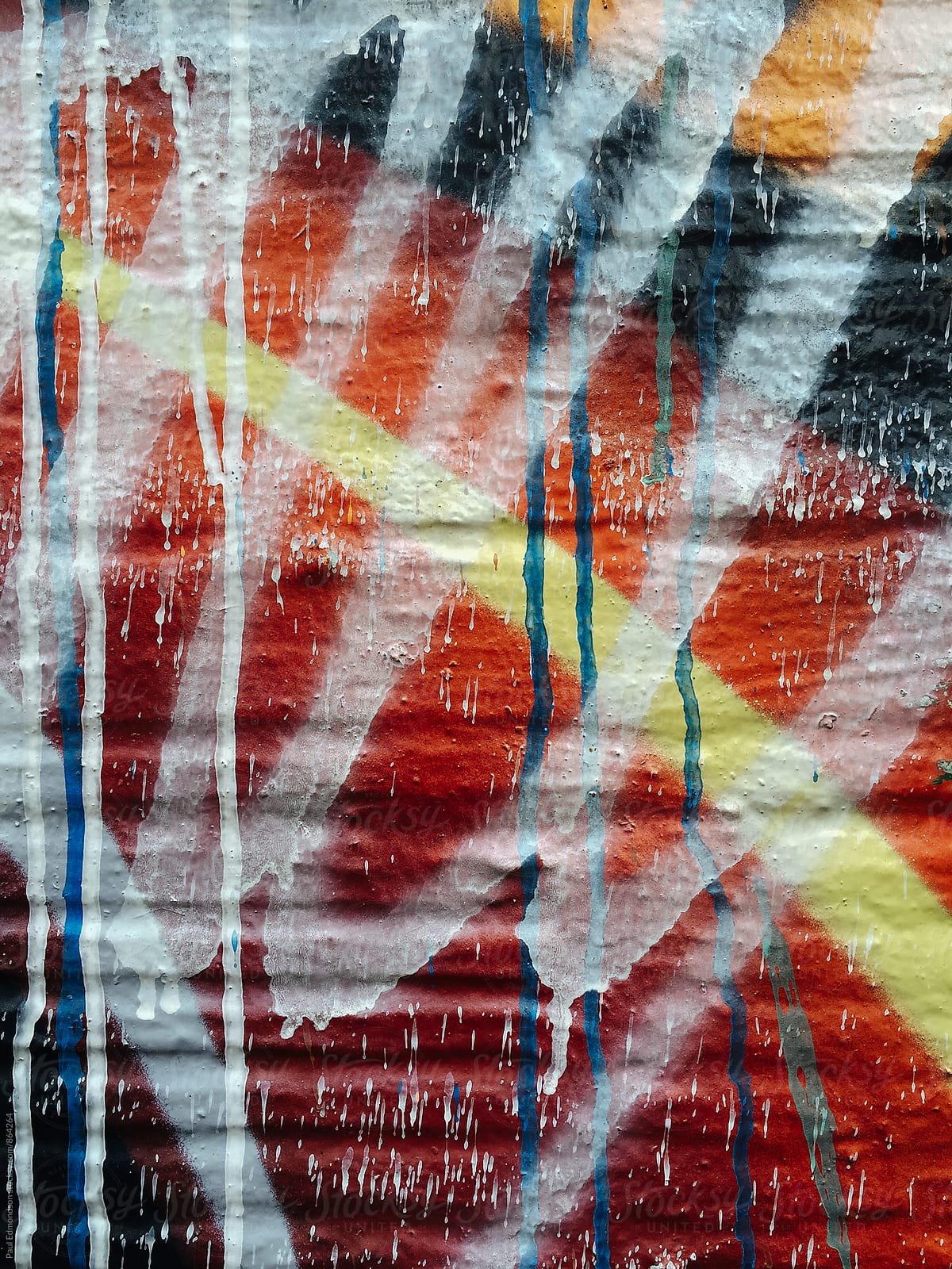 Colorful dripping paint and graffiti on building wall, close up
