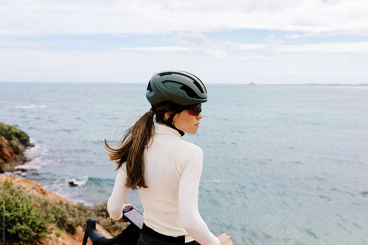 A professional cyclist gazing out at the sea next to her gravel bike