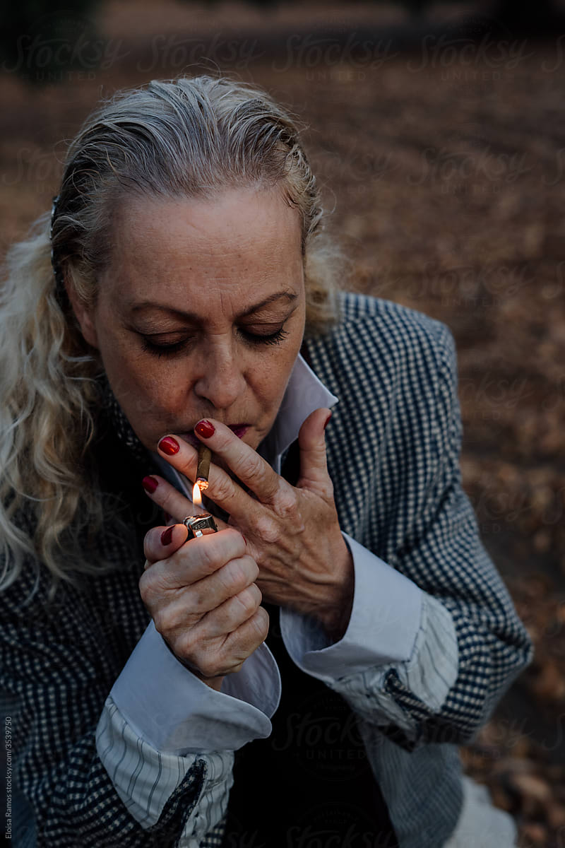Senior woman lighting a cigar in flamenco attitude at field