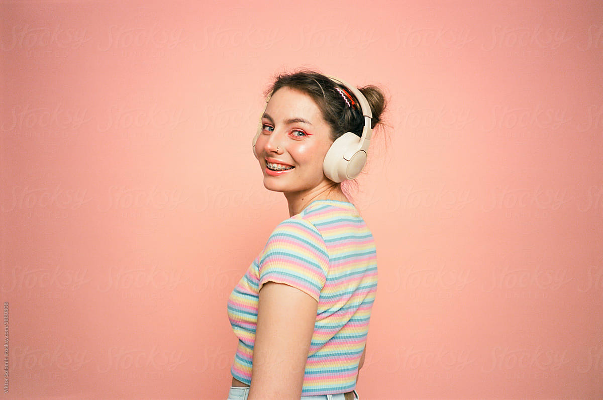 Smiling girl headphones listening music  peachy background
