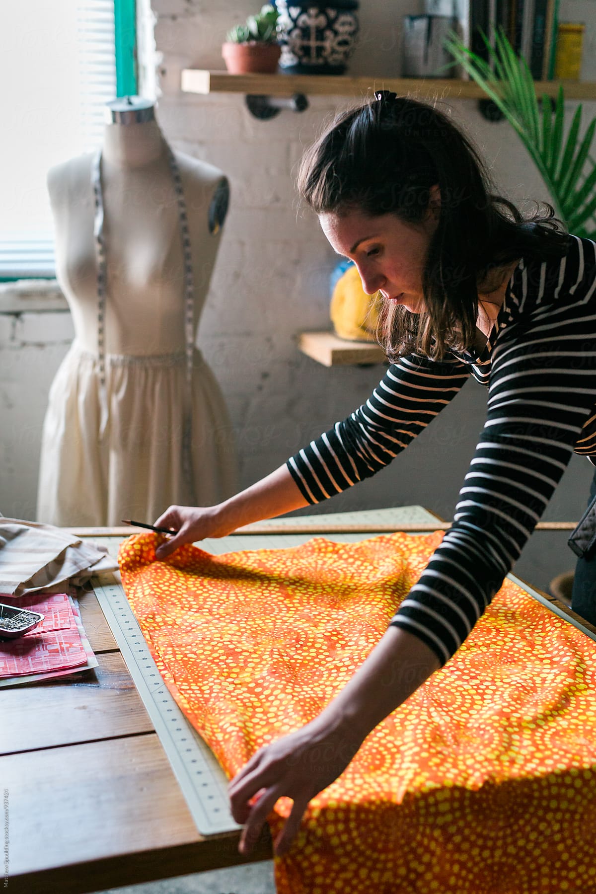 Designer measuring orange fabric for clothing pattern