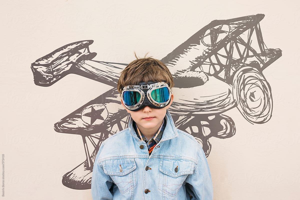 6 years old boy wearing goggles in front of an aeroplane painting