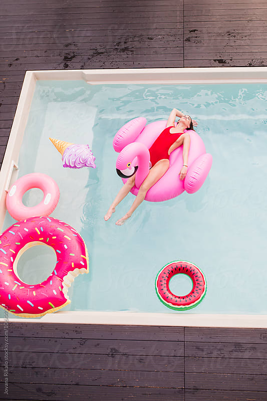 Beautiful young woman floating on a flamingo float in a swimming pool