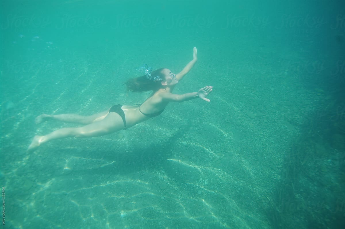 Young woman diving underwater in sunlight