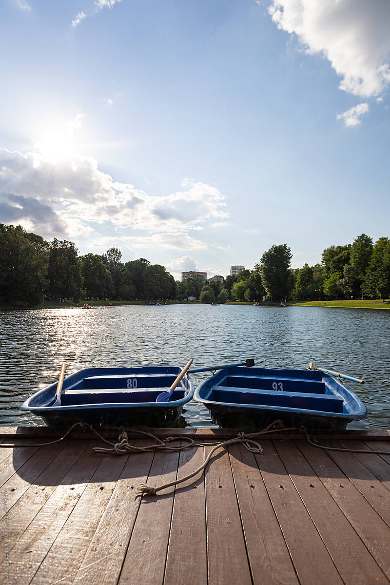 Two empty boats in front of a pond during a sunny summer day