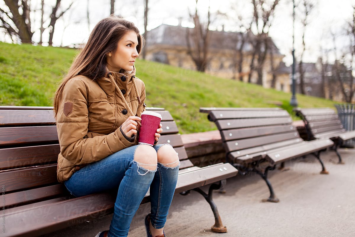Attractive young woman sitting on a bench at a local park