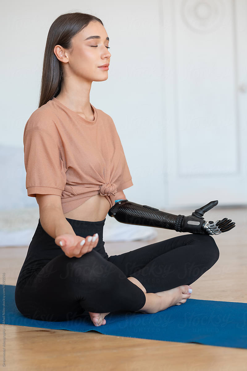 Woman with a prosthesis on her arm doing yoga at home