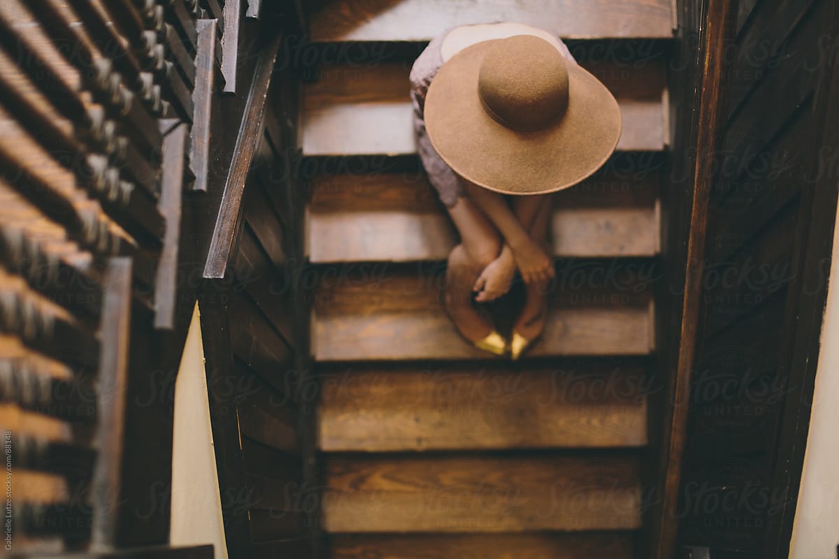 Girl sitting on wood stairs in wide brim hat