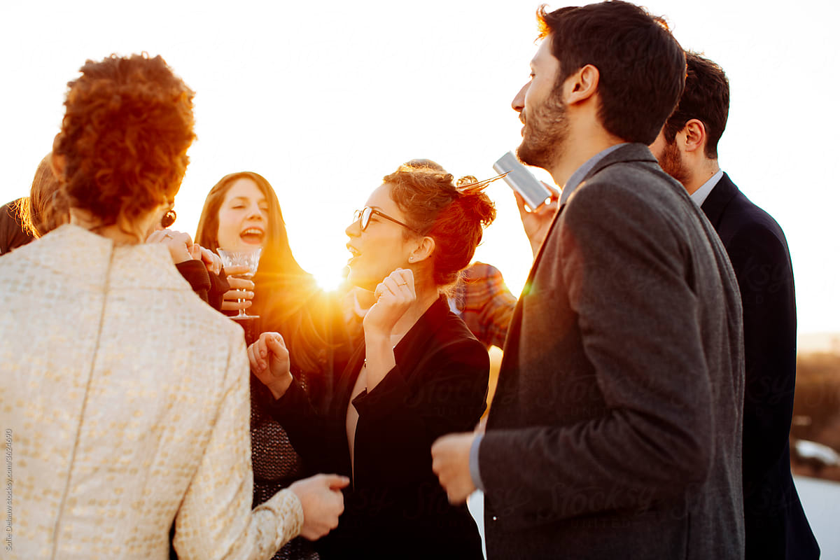 Cheerful friends in stylish wear talking during party in sunlight