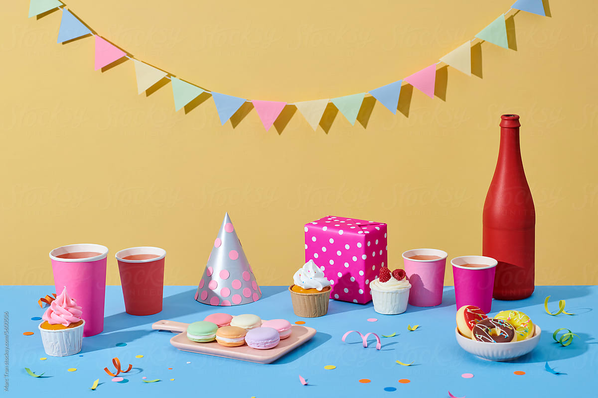 Birthday cake with sweets on white table near yellow pastel background