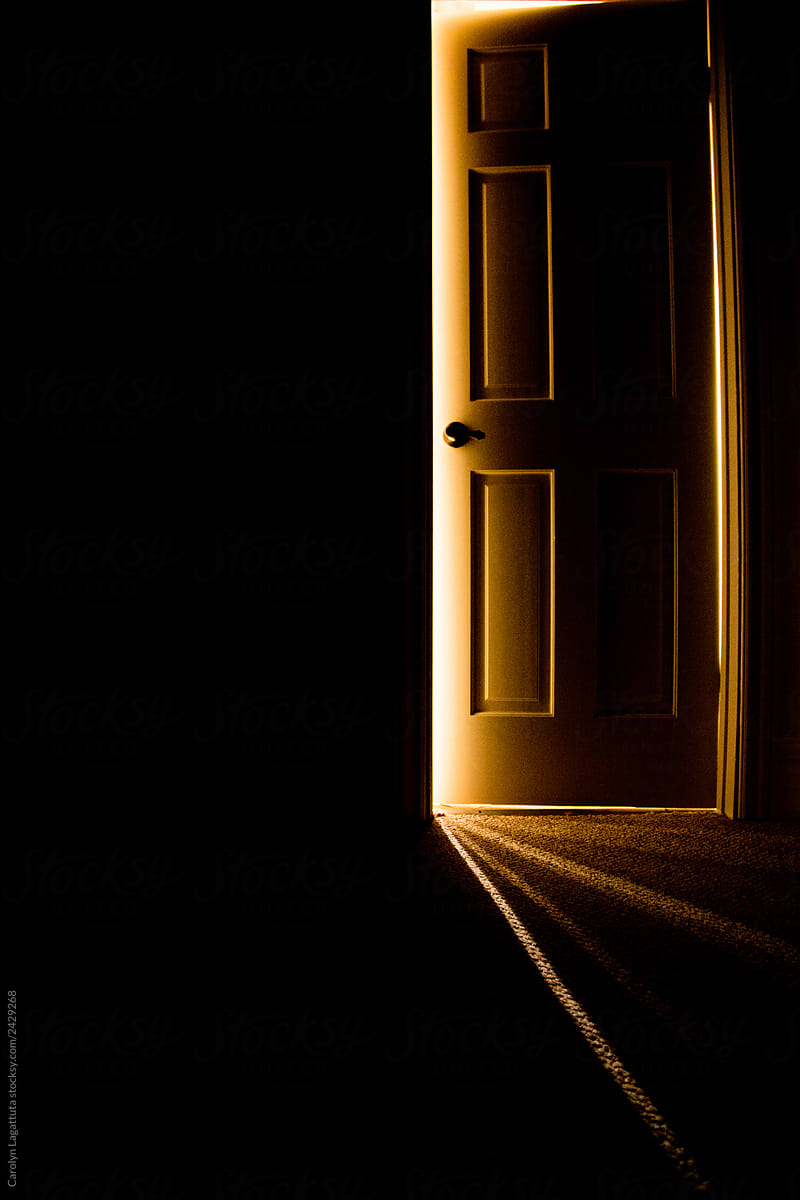 Dark hallway with a door with beams of light coming from behind it