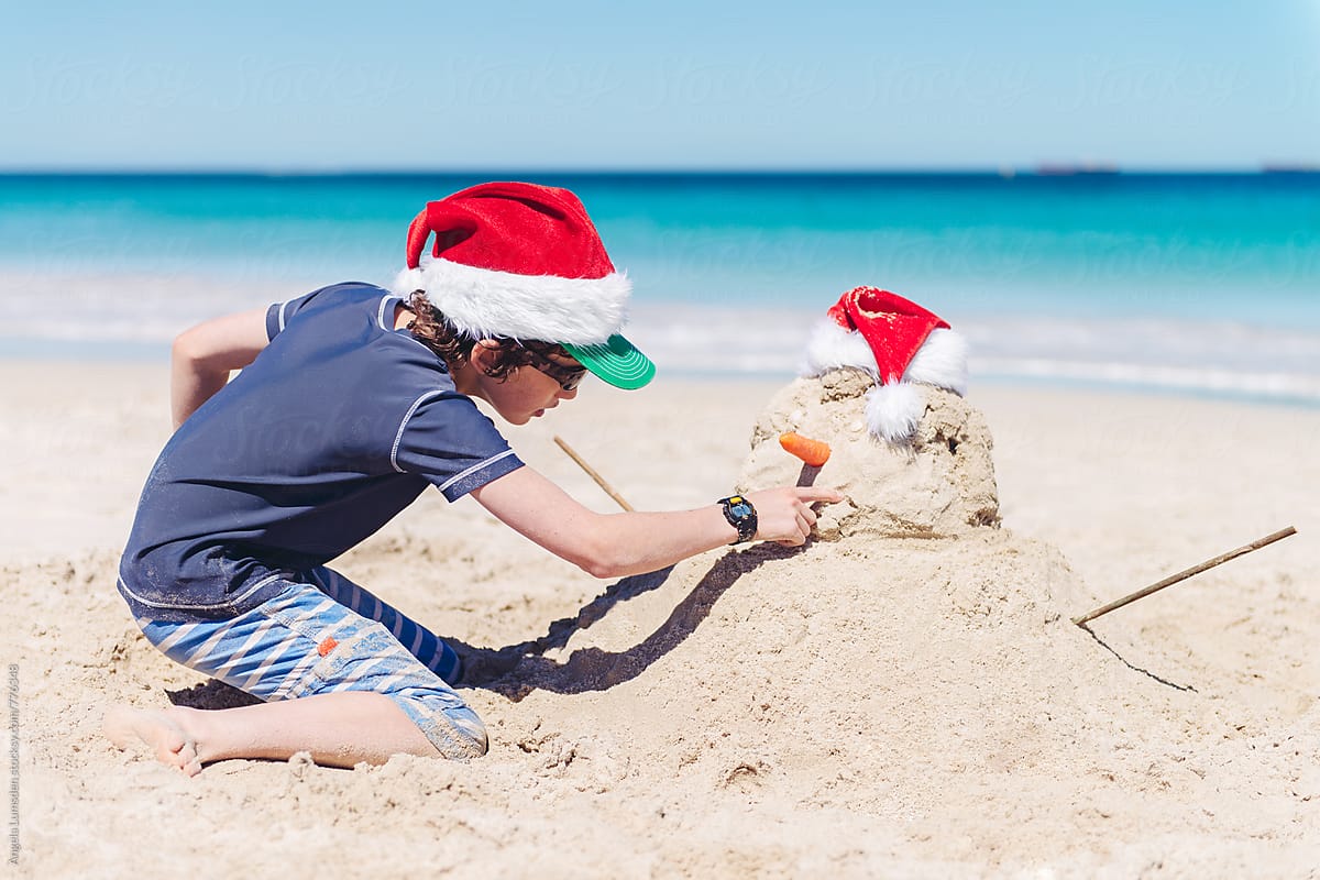 Boy making a sand snowman at the beach on Christmas day
